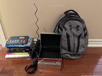 Group shot showing backpack, jewelry box open, zig-zag stand, stack of books/DVDs