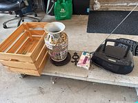 Overall lot showing wooden crate, porcelain vase on stand, Sony boombox, charger package and wall hook