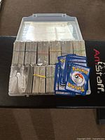Entire lot: plastic case open showing many rubber-banded stacks and several loose Pokémon cards on top