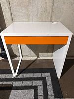 Front view of white desk showing orange drawer front and overall structure