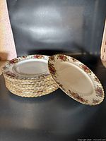 Twelve Royal Albert Old Country Rose plates stacked, showing floral decoration around edges with gold trim.