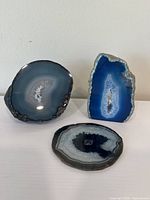 Three agate stones displayed together showing two polished slices and one standing geode with crystal interior.