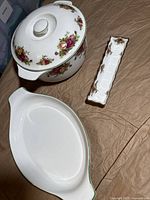 Three Royal Albert Old Country Rose porcelain serving pieces including a covered tureen with floral design, a white oval platter with floral accents on the side, and a small divided rectangular tray with floral motifs.
