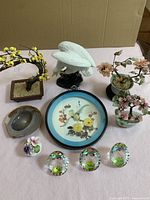 Full lot of decorative porcelain and glass items arranged on a pink surface with a brown cardboard background.