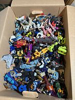 Top-down view of cardboard box filled with assorted Transformers figures in robot and vehicle modes