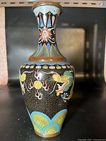 Front side of the vase showing the dragon and cloud patterns along with floral neck design and wave blue-green base.