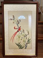 Full view of the framed Chinese painting showing two red birds on a magnolia tree branch with flowers and buds on light beige background, silk brocade matting and wooden frame.