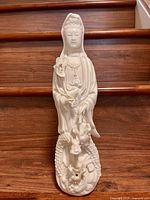 Front view of Chinese porcelain Guanyin figurine standing on dragon base.