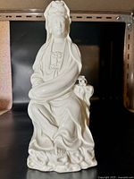 Front view of the white porcelain Guanyin figurine seated with flowing robes and calm expression.