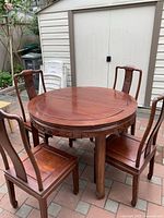 Round Chinese rosewood dining table with 4 matching chairs arranged outdoors on brick patio.