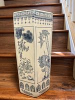 Front and side views of a tall hexagonal Chinese porcelain vase showing hand-painted blue illustrations of children playing, birds, bamboo, and lotus plants. The vase has decorative border bands at the top and bottom.
