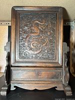 Front view of carved wooden table screen on stand