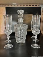 Full view of the cut glass crystal decanter set including decanter and two glasses on shelf