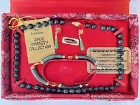 Open box showing necklace, bracelet, earrings with certificates and tags inside red satin fabric lining