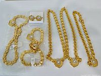 Full view of jewelry lot with three necklaces, three bracelets, and earrings arranged on a white background