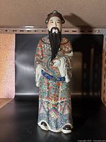 Front view of the figurine showing full body and detailed robe decoration with facial features and beard visible.