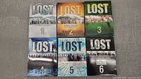 Photo showing all six Lost series DVD box sets with their distinctive cover art for seasons 1 through 6.