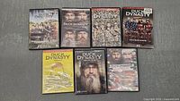 Front view of the seven Duck Dynasty DVD cases arranged in two rows showing cover art and titles for Seasons 1-5, Christmas special, and Life of Si.