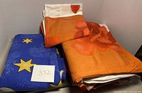 Folded two rose pattern duvet covers and one blue penguin cartoon duvet cover all folded and stacked