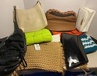 Nine assorted women's purses and pocketbooks displayed on a table, various materials and colors.
