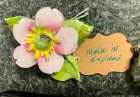 Porcelain flower pin in pink, yellow and green colors with tag 'Made in England'