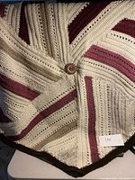 Top view of handmade crocheted afghan showing color pattern and center decorative button