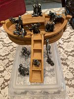 Overview of wooden ark and multiple pewter animal figures arranged on and around the ark with visible ladder and cabin structure on deck