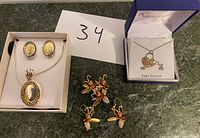 Three jewelry sets: oval pendant necklace with matching earrings, bee pin and earrings, cubic zirconia heart and bee necklace.