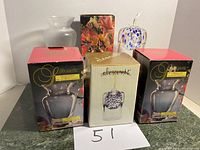 Photo showing two boxed Silhouette lead crystal vases, one boxed Elements diffuser, and one unboxed clear glass vase on a surface with a note marked 51.