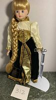Front view of porcelain Rapunzel doll with detailed gown, long braid, and display stand visible