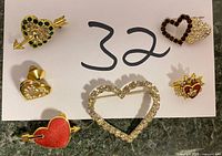 Six assorted heart pins showcased on a white background, each with different designs including rhinestones, enamel and gold-tone metal.