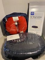Red neck pillow in plastic packaging along with Medline 16-inch ring cushion box displayed together.
