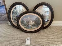 Three framed oval Marty Bell cottage prints grouped together showing their dark ornate frames and overall size relative to carpet texture.