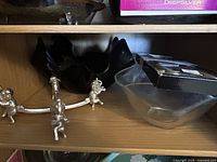 Metal stand with elephant figures resting on a shelf alongside a clear glass bowl.