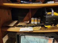 Chainsaw body, chain bar, and accompanying items on wooden shelf.