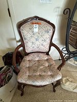 Full view of vintage wooden armchair with floral-patterned upholstery and cushion on seat, showing chair back and arms