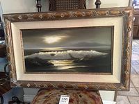 Full view of the framed painting showcasing ocean waves crashing with a decorative wooden frame and linen mat.