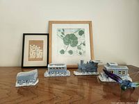 Photo showing two framed art prints and four blue ceramic trains arranged on wood surface