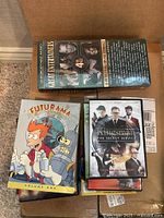 Box containing various DVDs including Futurama, Kingsman, Great Entertainers set