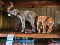Photo showing two carved wood elephants and one small wooden hippopotamus on a wooden shelf, highlighting condition and details.