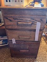 Front view of the solid wood 3-drawer file cabinet showing drawer fronts and wood grain texture with recessed handles and wear marks.