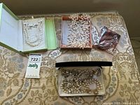 Pearl necklaces and jewelry spread on a fabric background showing various strands and boxes.