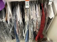 Overview of men's shirts on hangers mostly in dry cleaning protective bags.