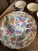 Tea set including luncheon plates, saucers, and floral patterned cups with scalloped edges.