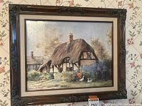 Framed print showing cottage scene in ornate wood frame