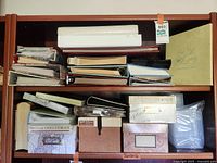Full shelf view showing assorted photo albums stacked horizontally and vertically, paired with multiple photo and video storage boxes of different sizes and styles.