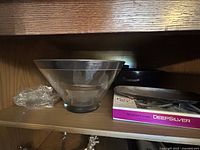 Black melamine salad bowl with silver base seen next to books on shelf