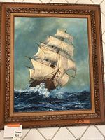 Frontal view of the framed oil painting of a sailing ship on a turbulent sea, showing the entire artwork and the frame.