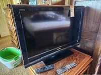 Sony Bravia television on wooden surface with two remotes in front, showing full front angle.