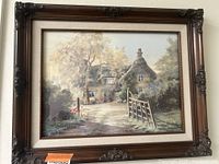 Framed print depicting an English countryside cottage scene with warm light and detailed brushwork.